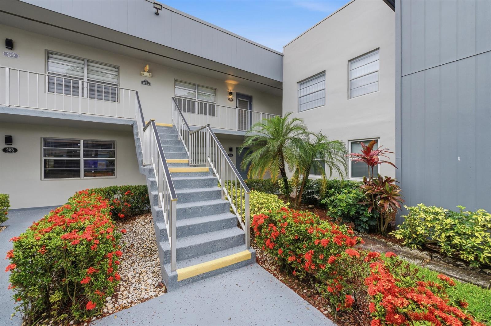 An exterior view of a two-story apartment building with concrete stairs and landscaped gardens — 330 Piedmont # 330, Delray Beach FL 33484, DELRAY BEACH, FL