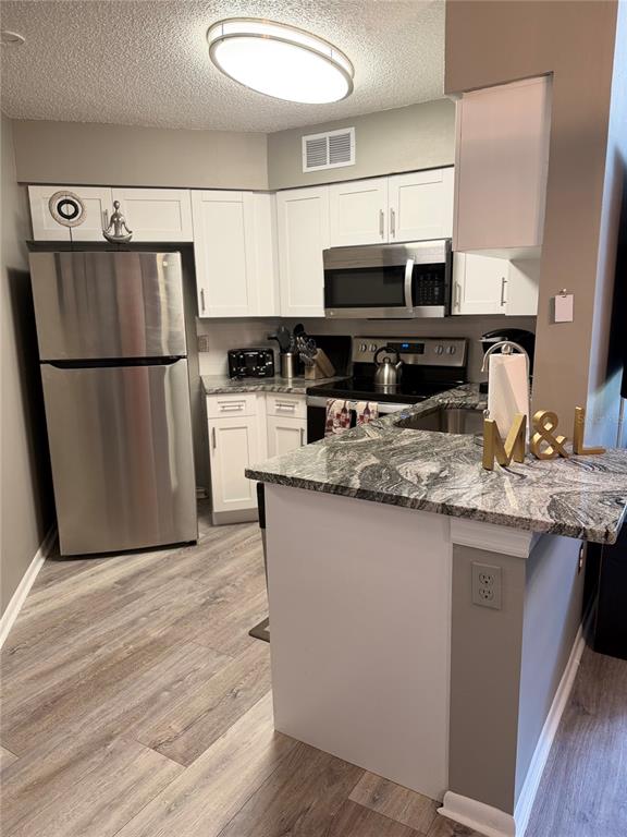 A kitchen features white cabinets, stainless steel appliances, and granite countertops with a breakfast bar — 3814 SOUTHPOINTE DRIVE UNIT 1, ORLANDO, FL