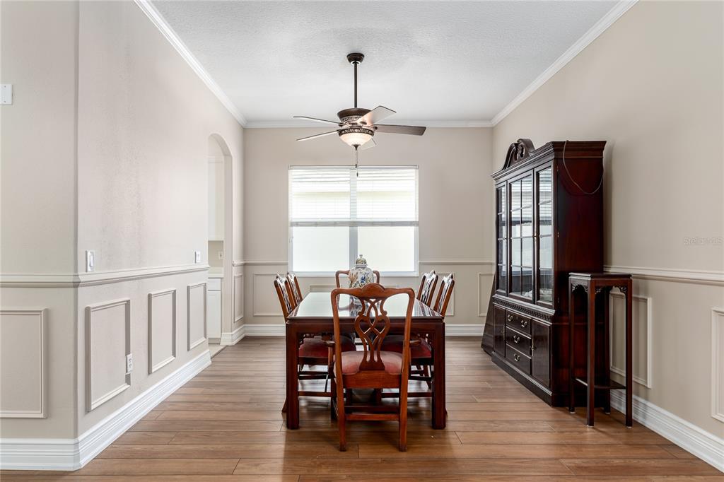 A dining room features wood flooring, wainscoting, a dark wood hutch, and a ceiling fan — 3208 WOODLAND FERN DRIVE, PARRISH, FL