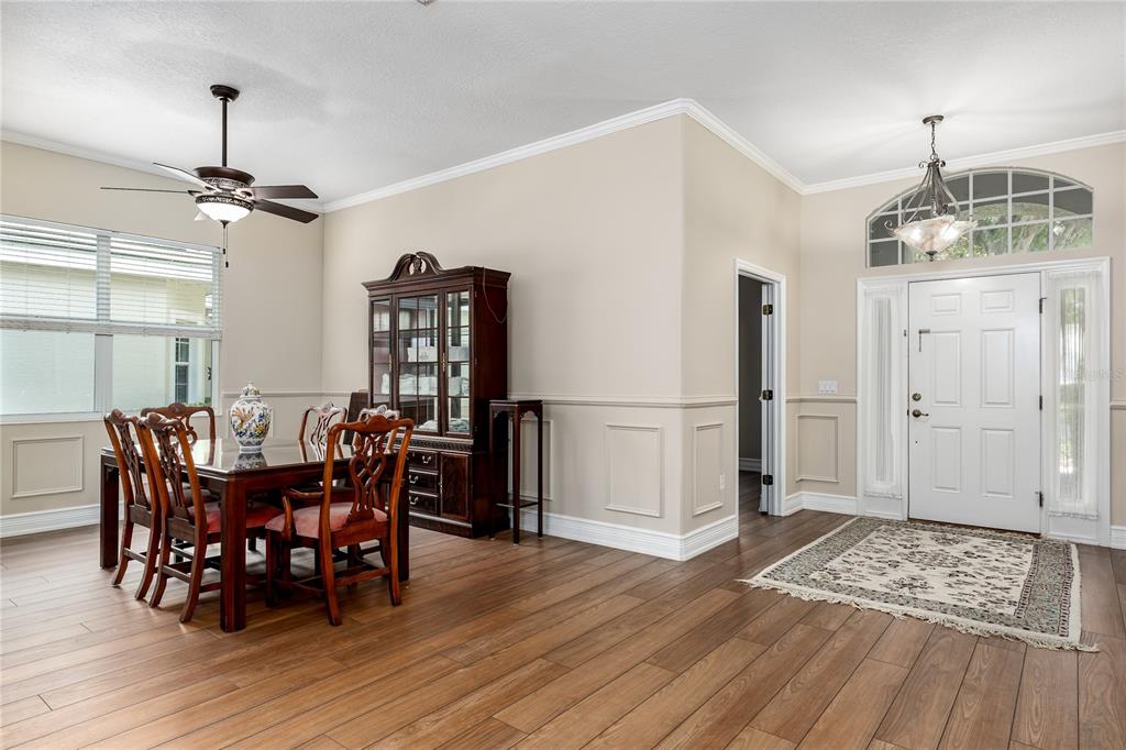 A dining room with wood floors, a china cabinet, and an entryway with a rug — 3208 WOODLAND FERN DRIVE, PARRISH, FL