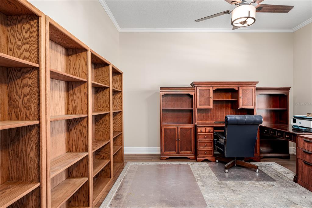 A home office features wood bookshelves, a matching desk with a hutch, and a ceiling fan — 3208 WOODLAND FERN DRIVE, PARRISH, FL