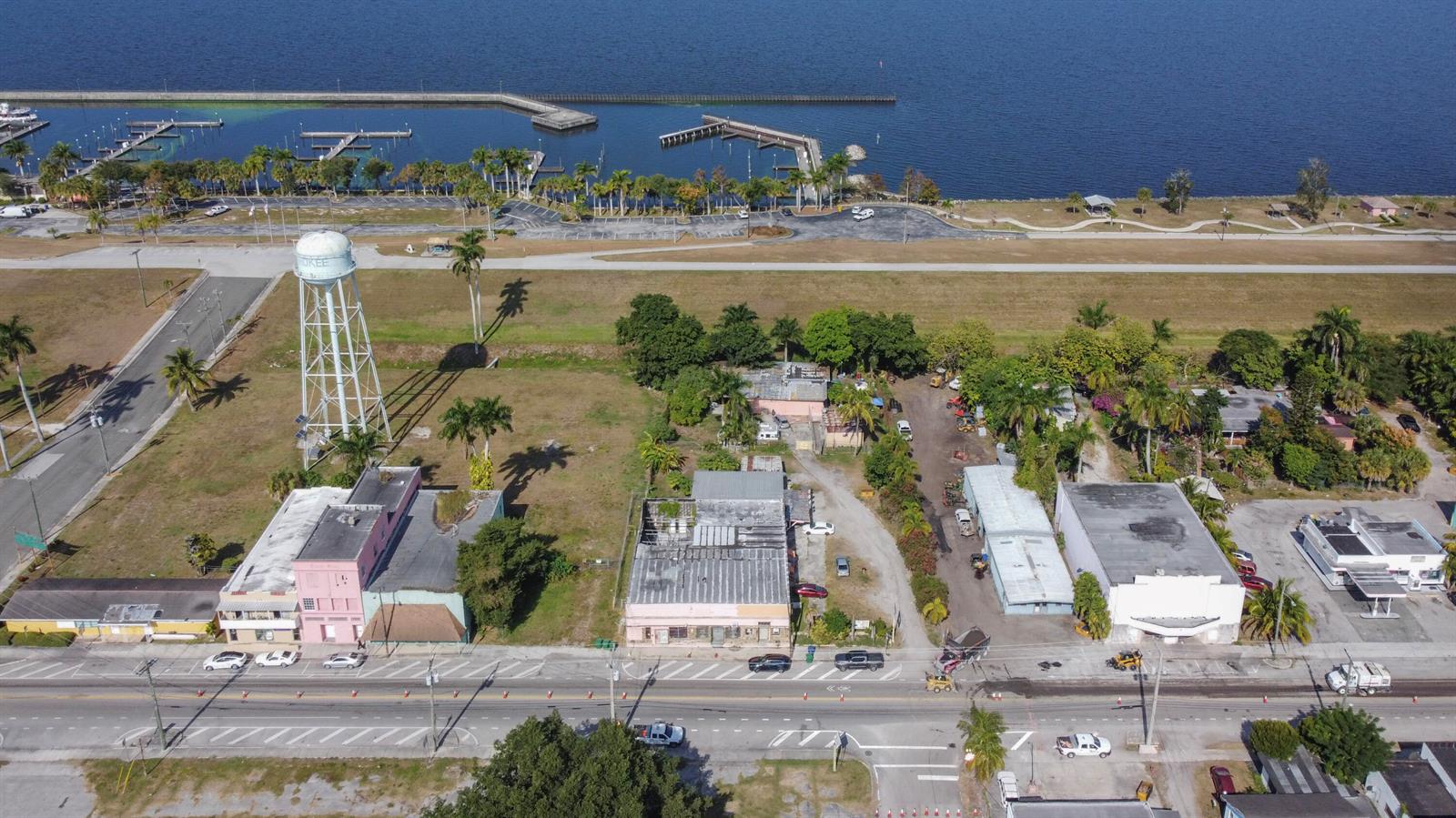 An aerial view shows a commercial area with a water tower near a waterfront marina — 185 E Main Street, Pahokee FL 33476, PAHOKEE, FL