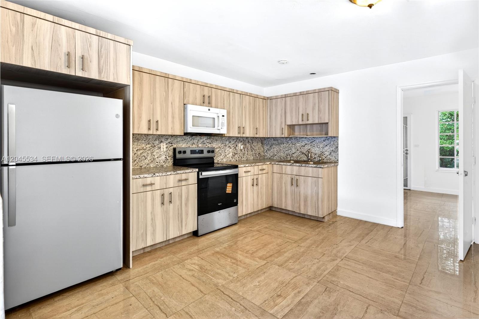A kitchen features light wood cabinets, granite countertops, stainless steel appliances, and tiled flooring — 1350 NE 149th St # 2, Miami FL 33161, MIAMI, FL