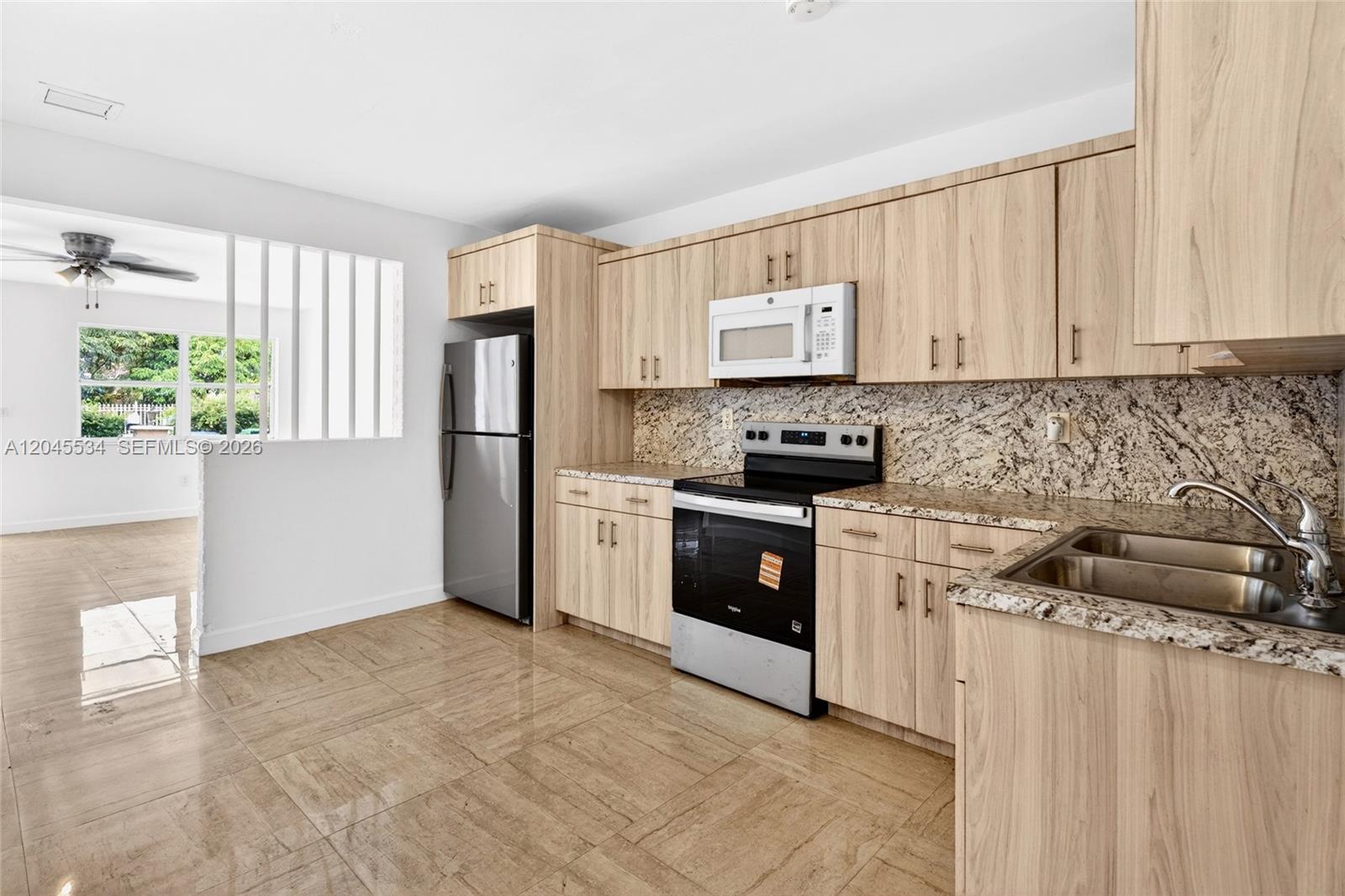 A kitchen features light wood cabinets, granite countertops, stainless steel appliances, and tiled flooring — 1350 NE 149th St # 2, Miami FL 33161, MIAMI, FL