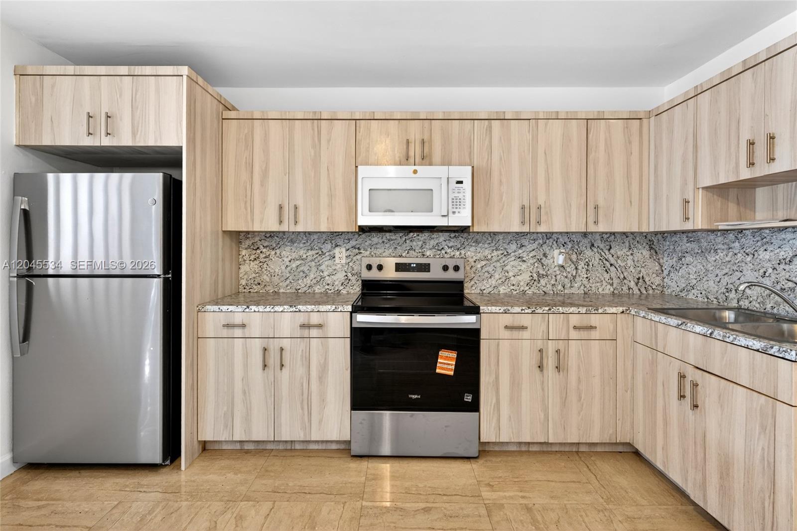 A kitchen features light wood cabinets, stainless steel appliances, and speckled granite countertops — 1350 NE 149th St # 2, Miami FL 33161, MIAMI, FL