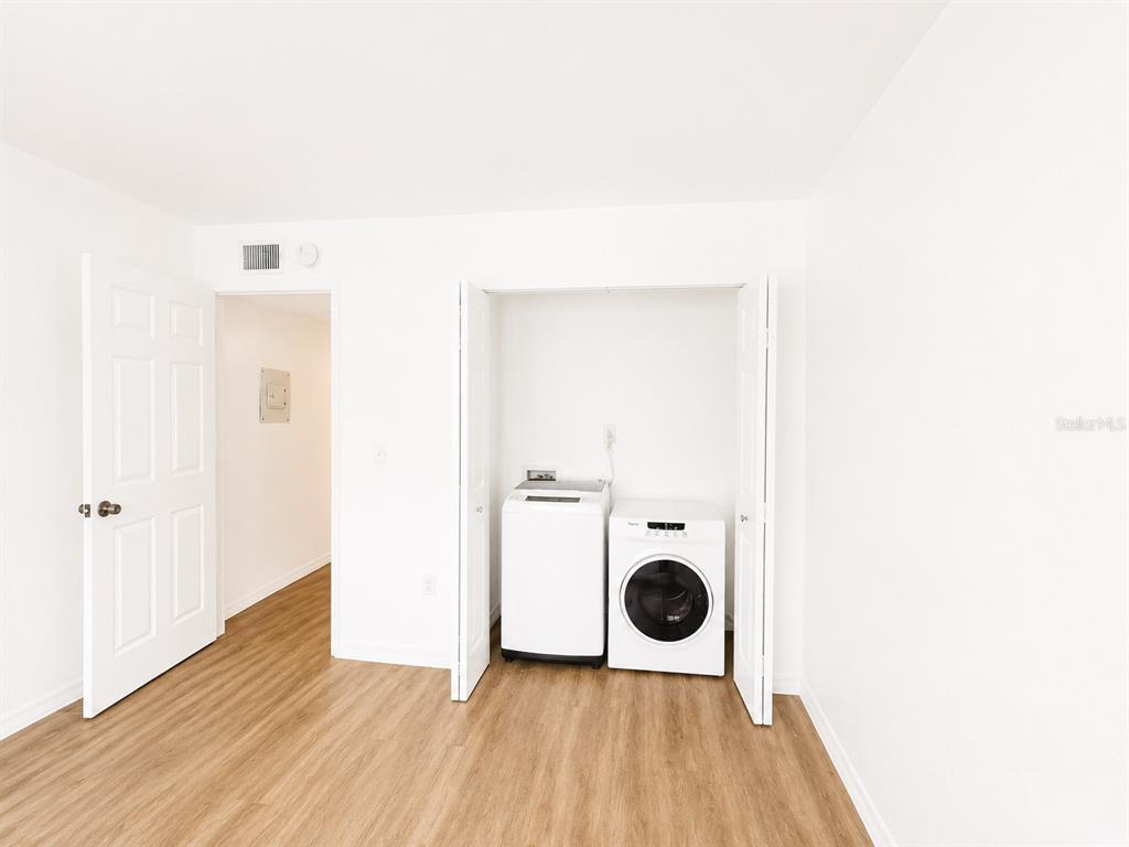 A room with light wood-look flooring features a laundry closet containing a washer and dryer — 5310 26TH STREET W UNIT 1406, BRADENTON, FL