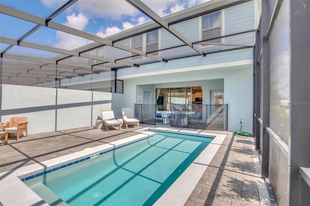 A screened-in patio features a rectangular swimming pool, lounge chairs, and a dining area — 8900 SYDNEY AVENUE, KISSIMMEE, FL