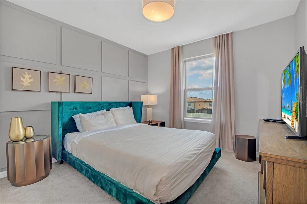 A bedroom features a teal velvet bed, gray paneled walls, and a wooden dresser — 8900 SYDNEY AVENUE, KISSIMMEE, FL