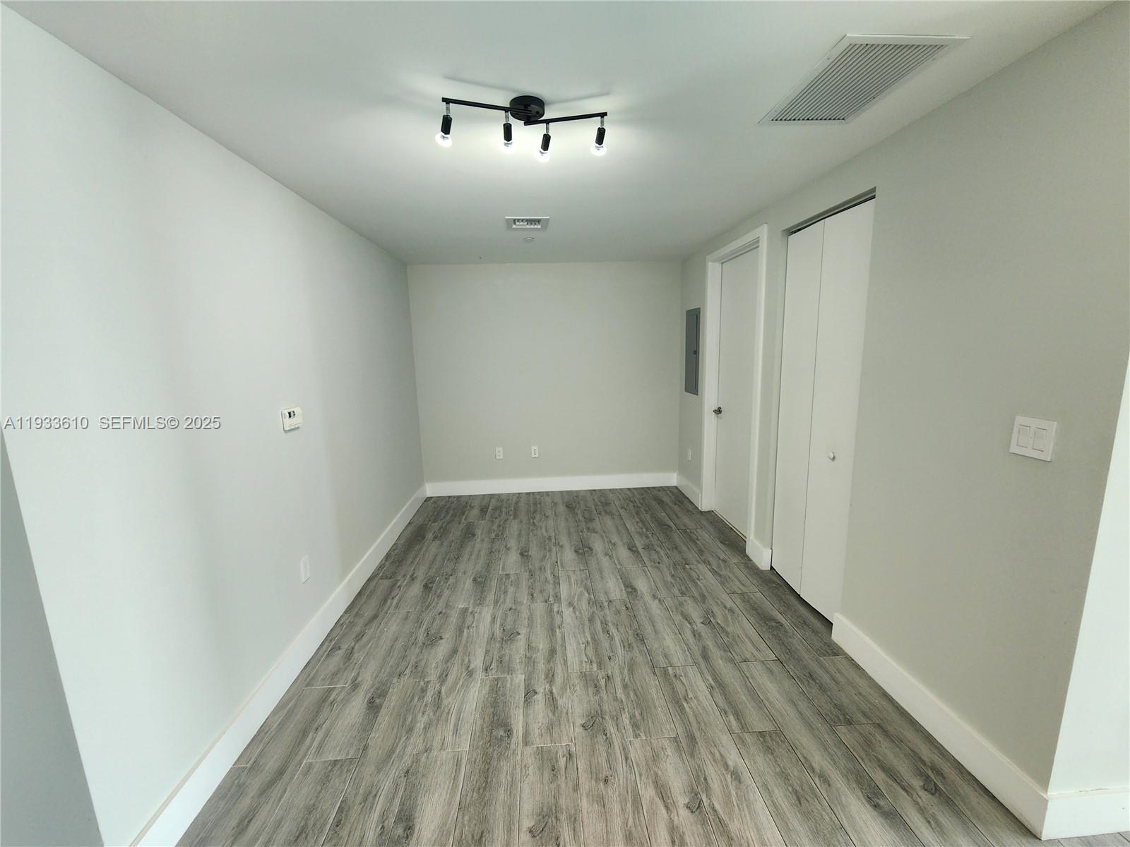 An empty room features light gray walls, wood-look flooring, a ceiling light, and white doors — 1300 S Miami Ave # 3502, Miami FL 33130, MIAMI, FL