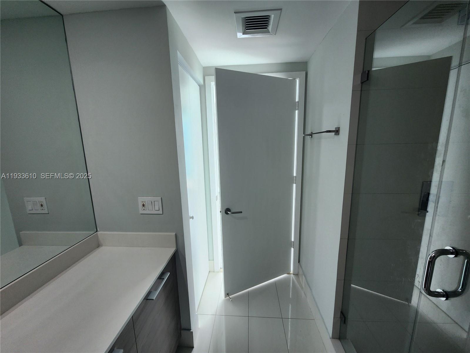 A bathroom features a white vanity, a large mirror, and a door leading outside — 1300 S Miami Ave # 3502, Miami FL 33130, MIAMI, FL