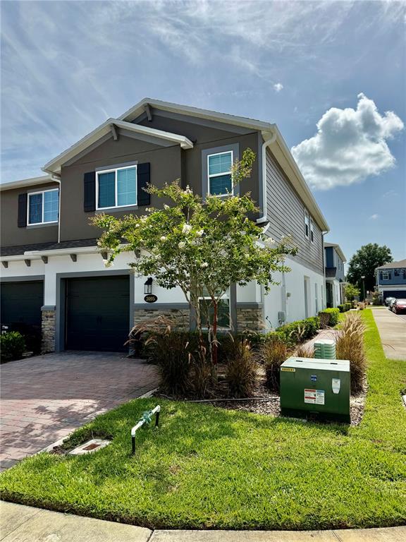 A two-story townhouse with a dark garage, stone accents, and a small tree in front — 3095 PADDLEBOX POINT, OVIEDO, FL
