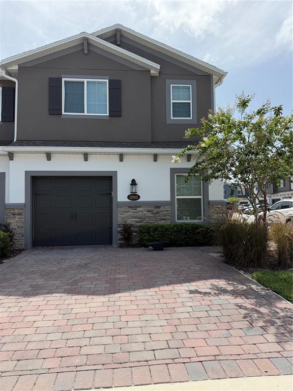 A two-story townhouse with a paved driveway, a one-car garage, and stone veneer accents — 3095 PADDLEBOX POINT, OVIEDO, FL