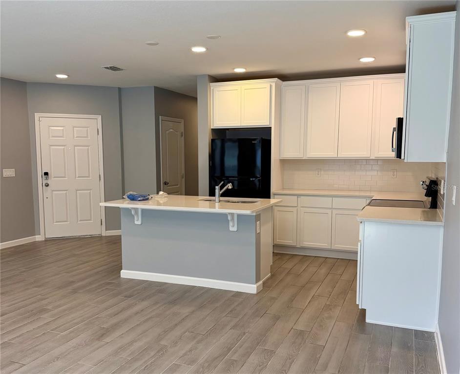 A kitchen with white cabinets, a central island, and gray wood-look flooring — 3095 PADDLEBOX POINT, OVIEDO, FL