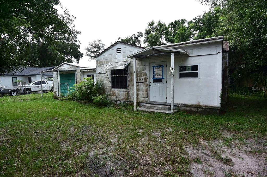 A small, weathered white house with a metal awning and a front porch — 1422 W HUMPHREY STREET, TAMPA, FL