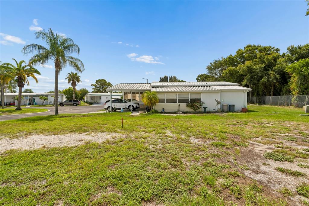 A grassy lot sits between manufactured homes under the shade of large tree branches — 9790 66TH STREET N UNIT 365, PINELLAS PARK, FL