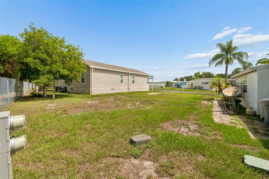 The exterior of a single-story beige house with a metal carport and a grassy yard — 9790 66TH STREET N UNIT 365, PINELLAS PARK, FL