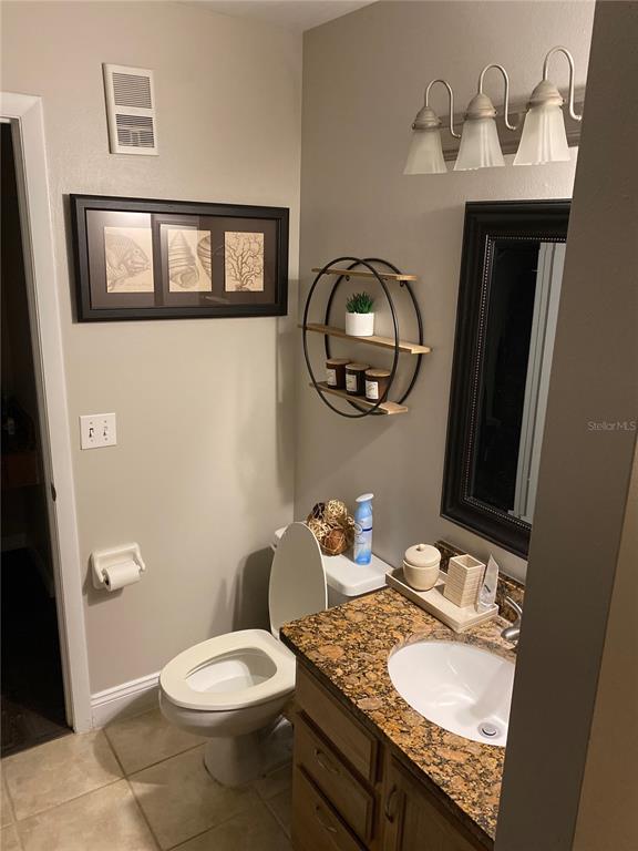 A bathroom features a granite vanity, a round wall shelf, and a toilet — 482 N PIN OAK PLACE UNIT 304, LONGWOOD, FL