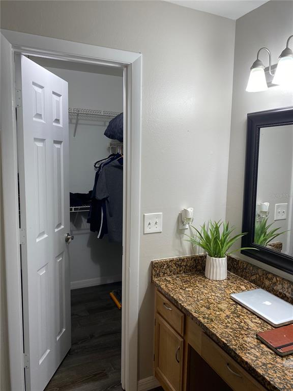 A bathroom vanity with a granite countertop sits beside an open doorway to a closet — 482 N PIN OAK PLACE UNIT 304, LONGWOOD, FL