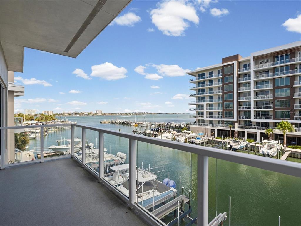 A balcony with a glass railing overlooks a marina with boats and a large building — 868 N OSCEOLA AVENUE, CLEARWATER, FL