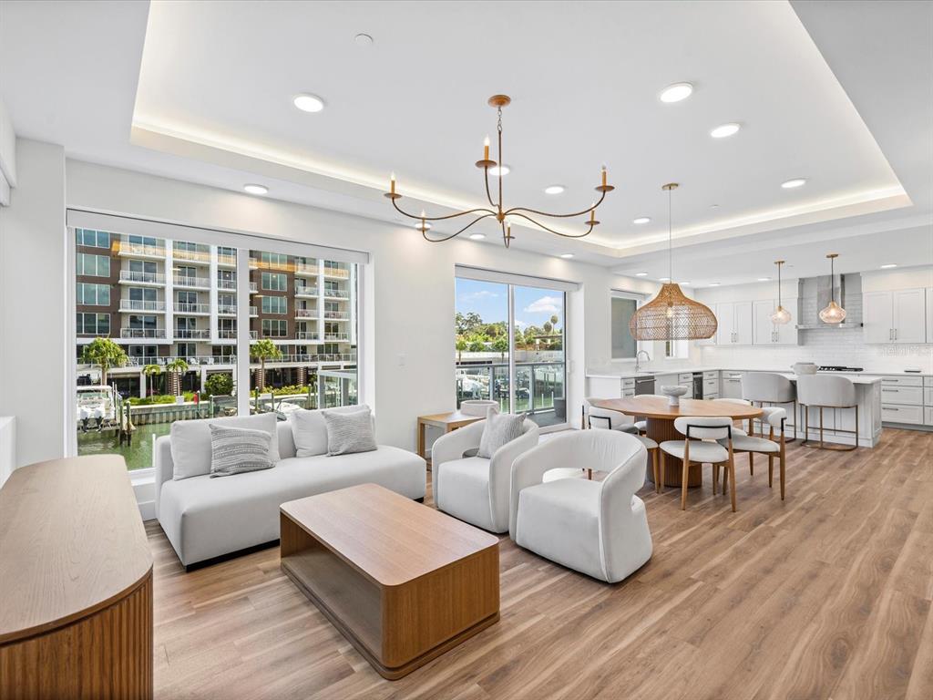 An open-concept living and dining area features light wood floors, white furniture, and large windows — 868 N OSCEOLA AVENUE, CLEARWATER, FL