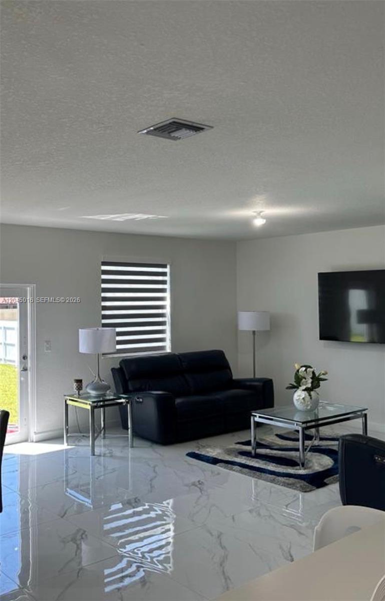 A living room features white marble-look tile floors, a black sofa, and a wall-mounted television — 12760 SW 215th Ter, Miami FL 33177, MIAMI, FL