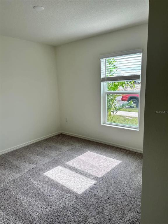 A small, empty bedroom features gray carpet, white walls, and a window with blinds — 3863 AXIS VALLEY PLACE, ST CLOUD, FL
