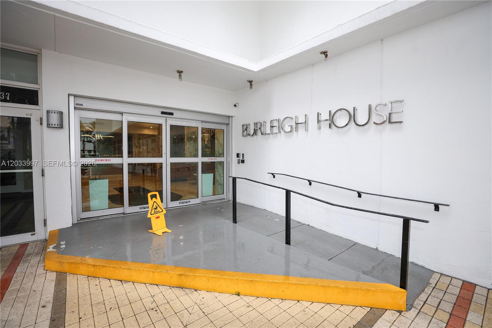 The exterior entrance of a building features a ramp, sliding glass doors, and signage — 7135 Collins Ave # 735, Miami Beach FL 33141, MIAMI BEACH, FL