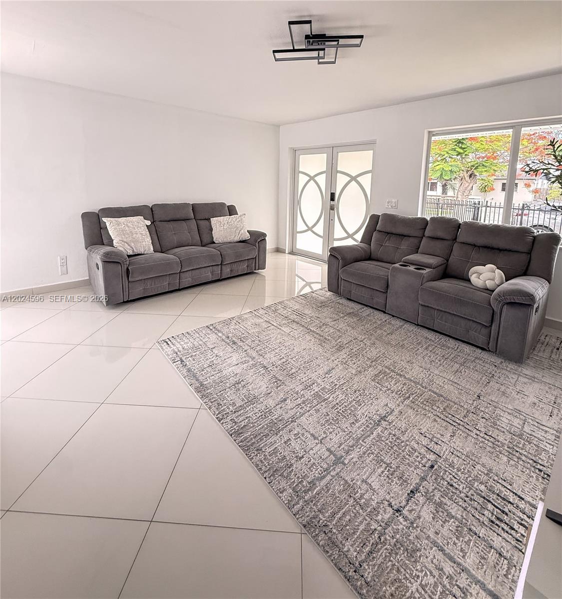 A living room features two gray sofas, a large area rug, and white tile flooring — 20130 SW 106th Ave, Cutler Bay FL 33189, CUTLER BAY, FL