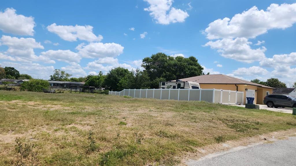 A vacant grassy lot sits next to a house with a white vinyl privacy fence — 3143 JACKSON DRIVE, HOLIDAY, FL
