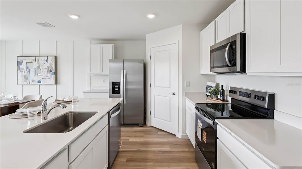 A modern kitchen features white cabinets, stainless steel appliances, and a large island with sink — 9817 SE 161ST LANE ROAD, SUMMERFIELD, FL