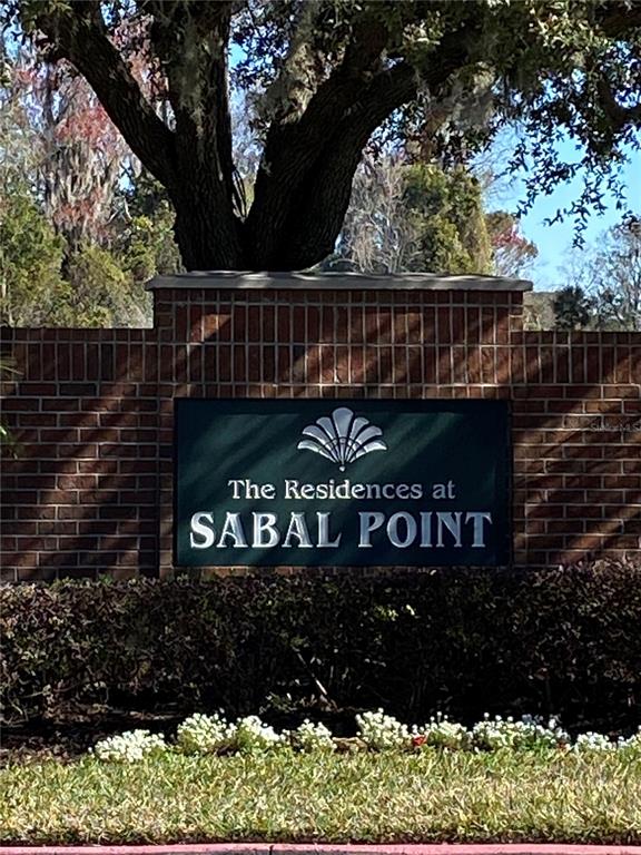 A brick wall displays a sign for The Residences at Sabal Point under a tree — 404 SUMMIT RIDGE PLACE UNIT 212, LONGWOOD, FL