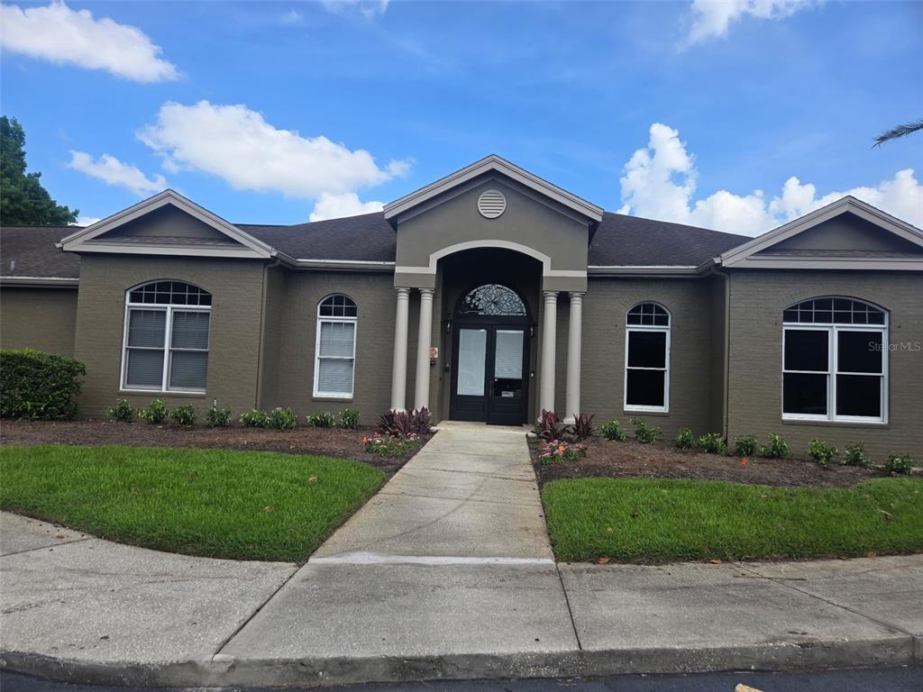 A single-story building with a dark brick exterior, arched windows, and a columned entryway — 404 SUMMIT RIDGE PLACE UNIT 212, LONGWOOD, FL