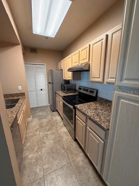 A galley kitchen features light wood cabinets, granite countertops, stainless steel appliances, and tile flooring — 404 SUMMIT RIDGE PLACE UNIT 212, LONGWOOD, FL