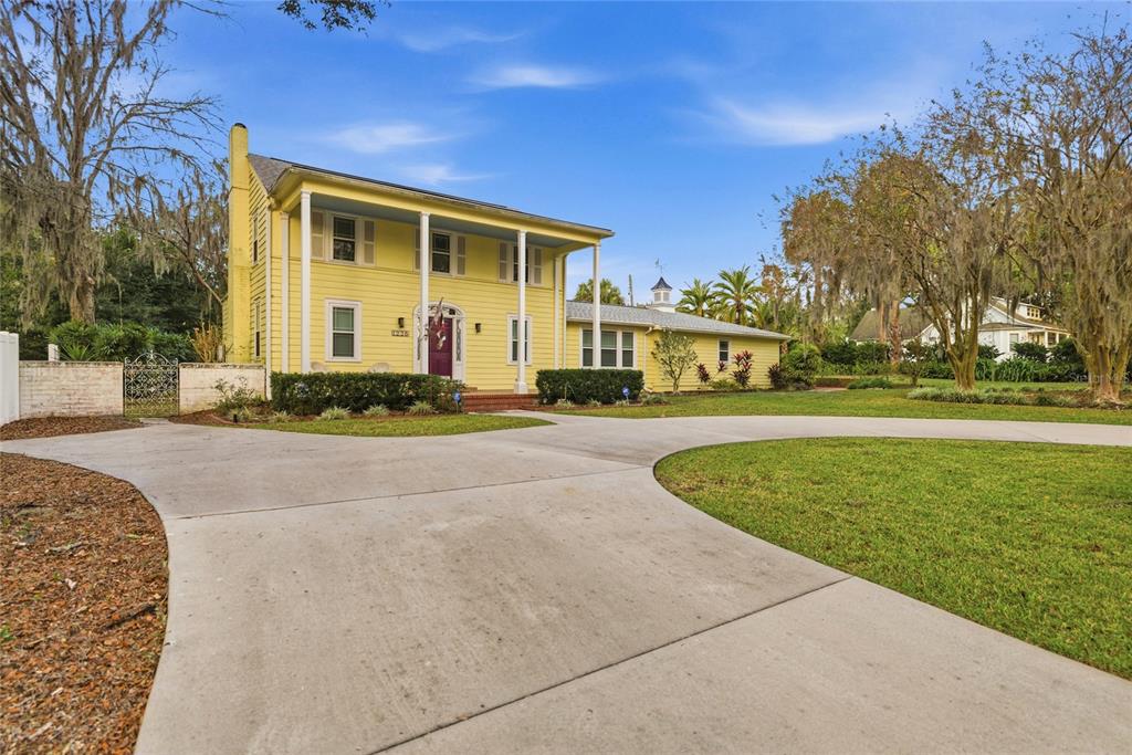 A two-story yellow house with a white porch and a curved concrete driveway — 1226 SE 9TH AVENUE, OCALA, FL