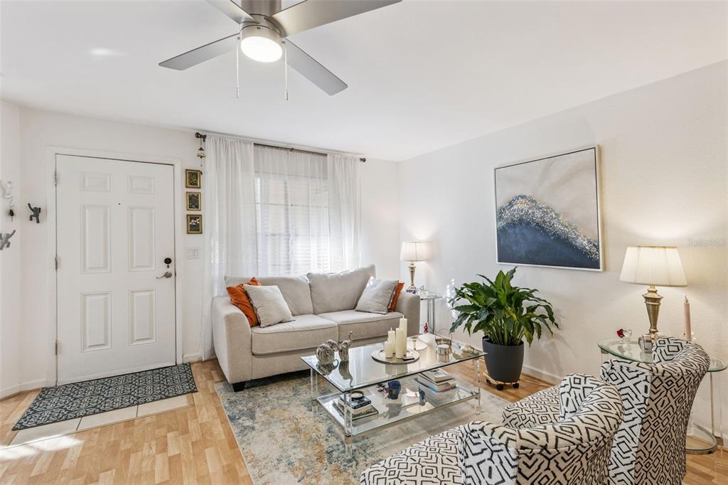 A living room features a light-colored sofa, patterned armchairs, a glass coffee table, and artwork — 415 LAKEPOINTE DRIVE UNIT 103, ALTAMONTE SPRINGS, FL