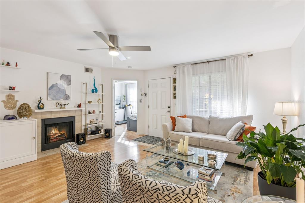 A living room features a fireplace, a glass coffee table, patterned armchairs, and a sofa — 415 LAKEPOINTE DRIVE UNIT 103, ALTAMONTE SPRINGS, FL