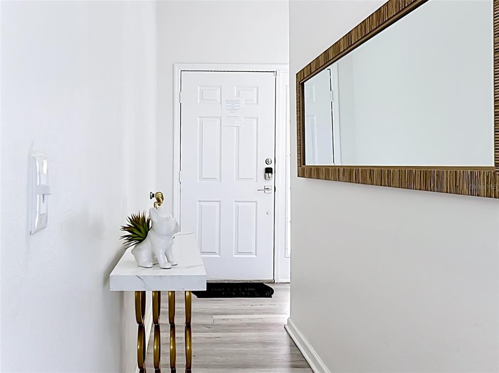A white entryway features a marble-topped console table, a wall mirror, and a front door — 336 HILLCREST DRIVE, DAVENPORT, FL