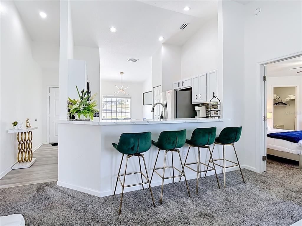 A kitchen with a white marble breakfast bar and four green velvet bar stools — 336 HILLCREST DRIVE, DAVENPORT, FL