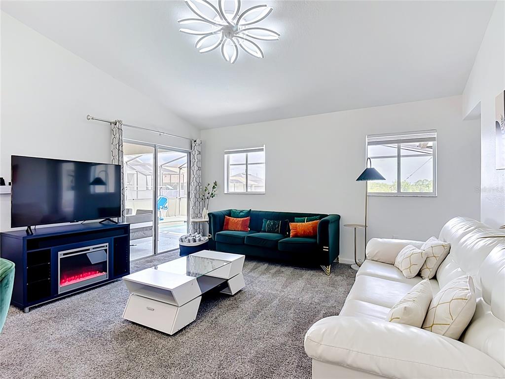 A living room features a dark green sofa, white leather sofa, and a glass coffee table — 336 HILLCREST DRIVE, DAVENPORT, FL