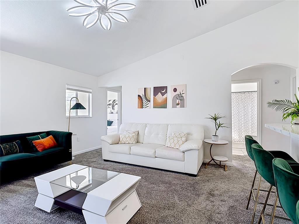 A living room features a white sofa, a dark green sofa, and a modern coffee table — 336 HILLCREST DRIVE, DAVENPORT, FL