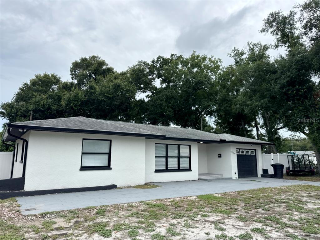 A white single-story house with a dark roof, black window frames, and a garage — 3780 51ST STREET N, ST PETERSBURG, FL