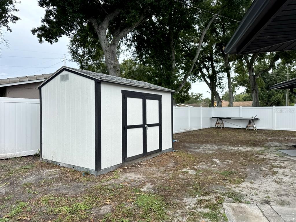 A white storage shed with black trim sits in a backyard enclosed by white fencing — 3780 51ST STREET N, ST PETERSBURG, FL