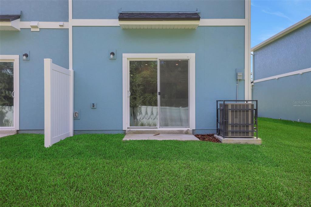 The exterior of a blue townhouse features a sliding glass door and an air conditioner — 733 SAILOR GROVE LANE, JACKSONVILLE, FL