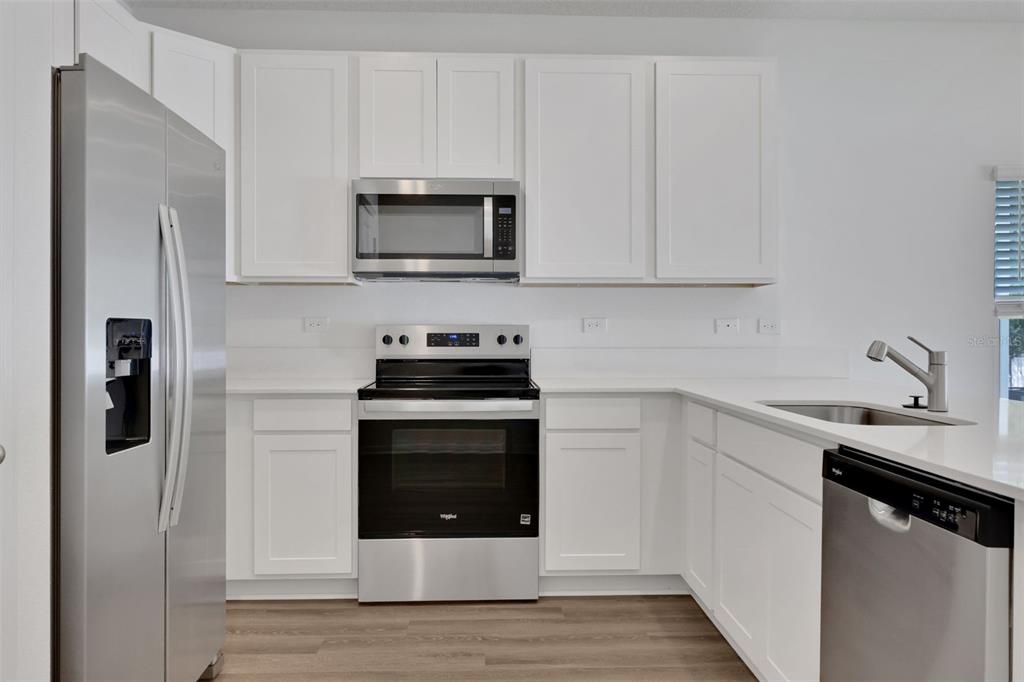 A kitchen with white cabinets, stainless steel appliances, and light wood-look flooring — 733 SAILOR GROVE LANE, JACKSONVILLE, FL