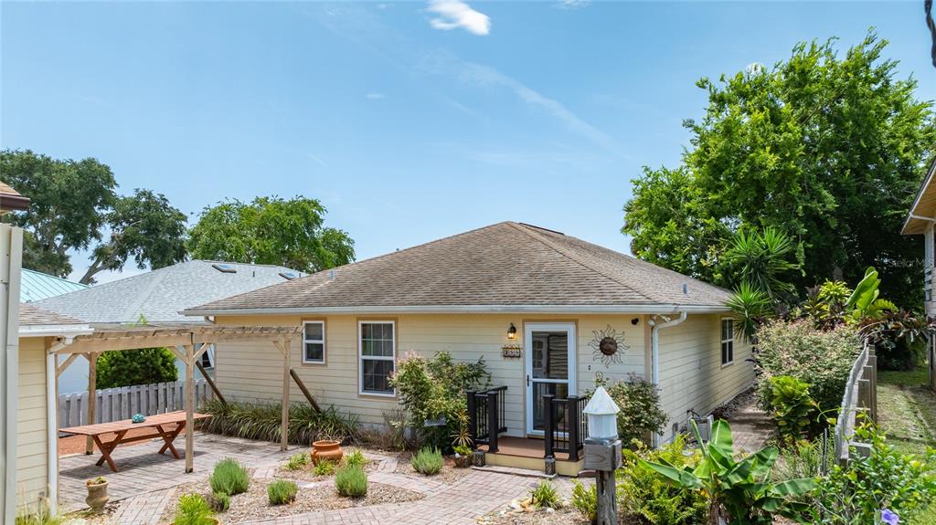 A yellow house with a hip roof, a wooden pergola, and a brick patio — 235 RANDLE AVENUE, OAK HILL, FL