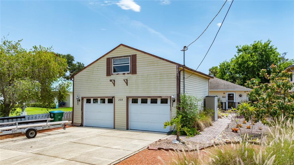 A detached two-car garage with light siding and a small upper window stands outdoors — 235 RANDLE AVENUE, OAK HILL, FL