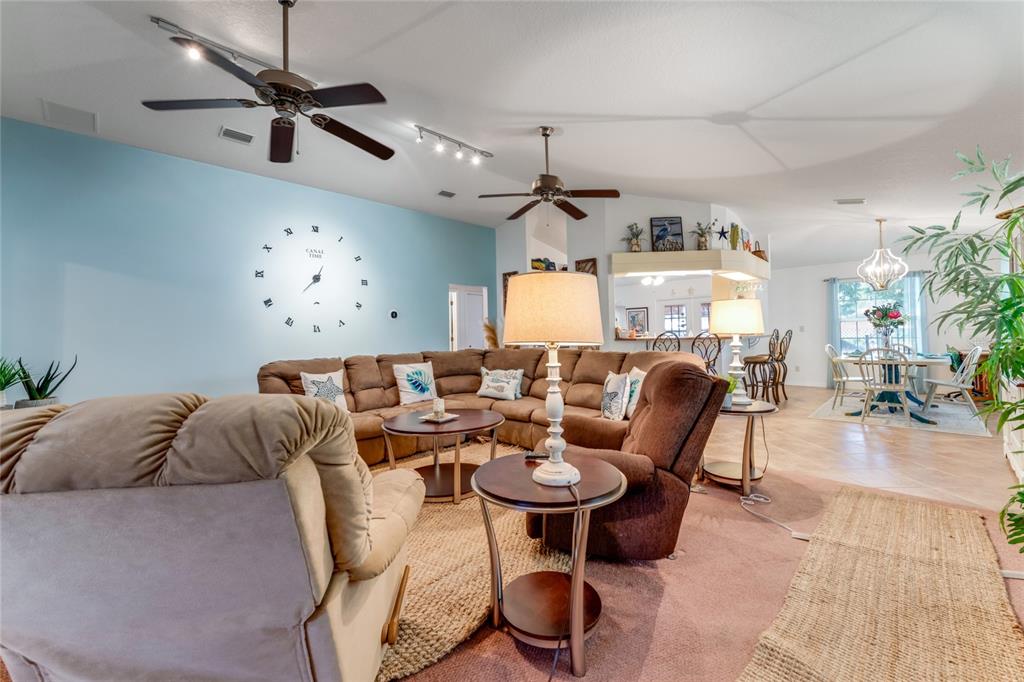 A living room features a large sectional sofa, a wall clock, and two ceiling fans — 235 RANDLE AVENUE, OAK HILL, FL