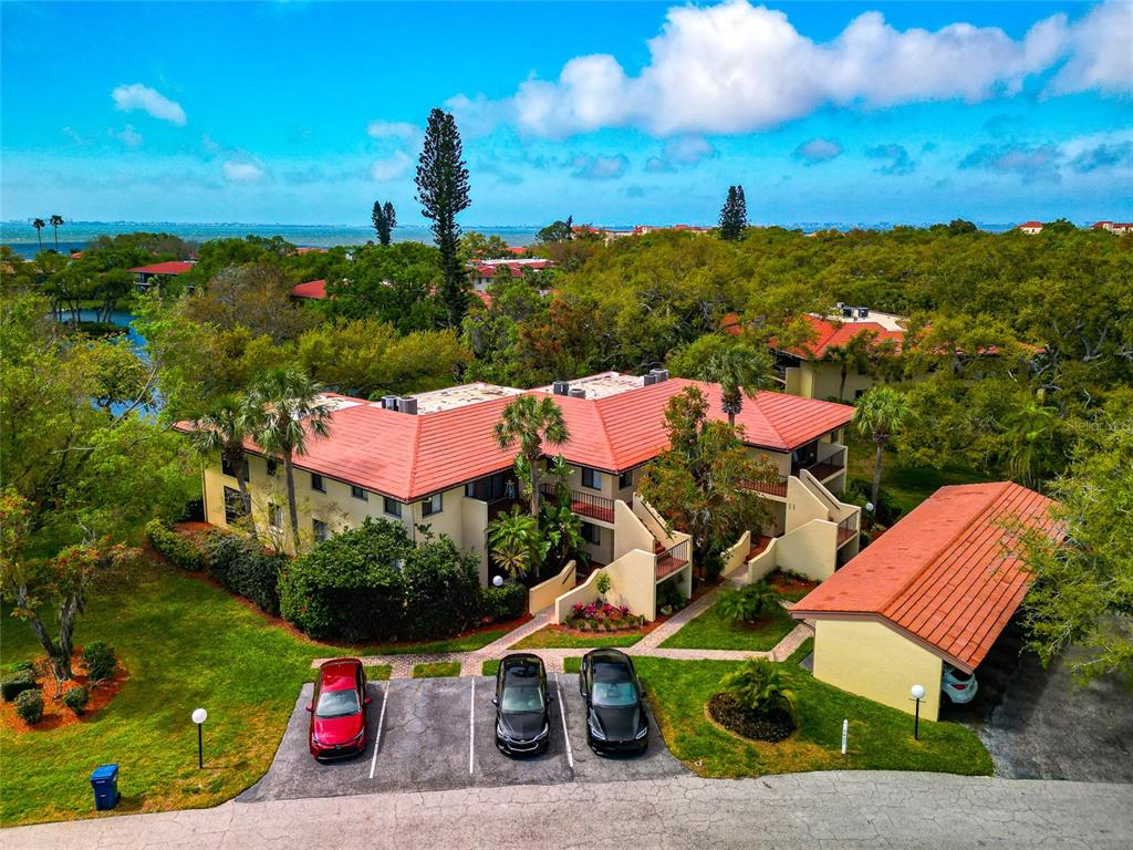 An aerial view of a multi-story apartment building with a red tile roof and parking — 6423 EGRET LANE UNIT 406, BRADENTON, FL