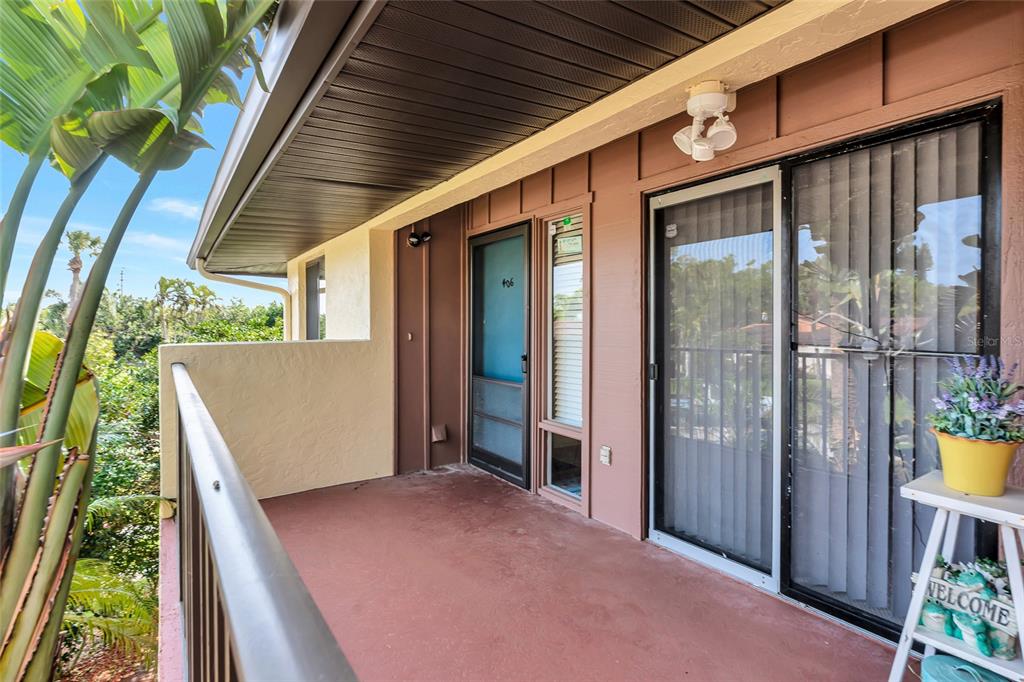 A covered balcony features a brown door, sliding glass doors, and a metal railing — 6423 EGRET LANE UNIT 406, BRADENTON, FL