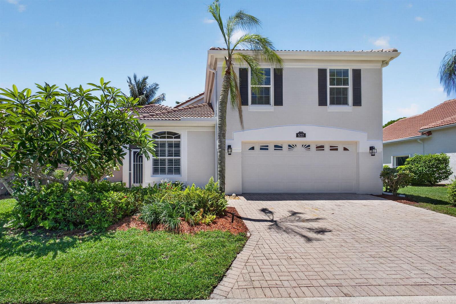 A two-story house with a beige stucco exterior, a tile roof, and a paved driveway — 5137 Elpine Way, Riviera Beach FL 33418, RIVIERA BEACH, FL